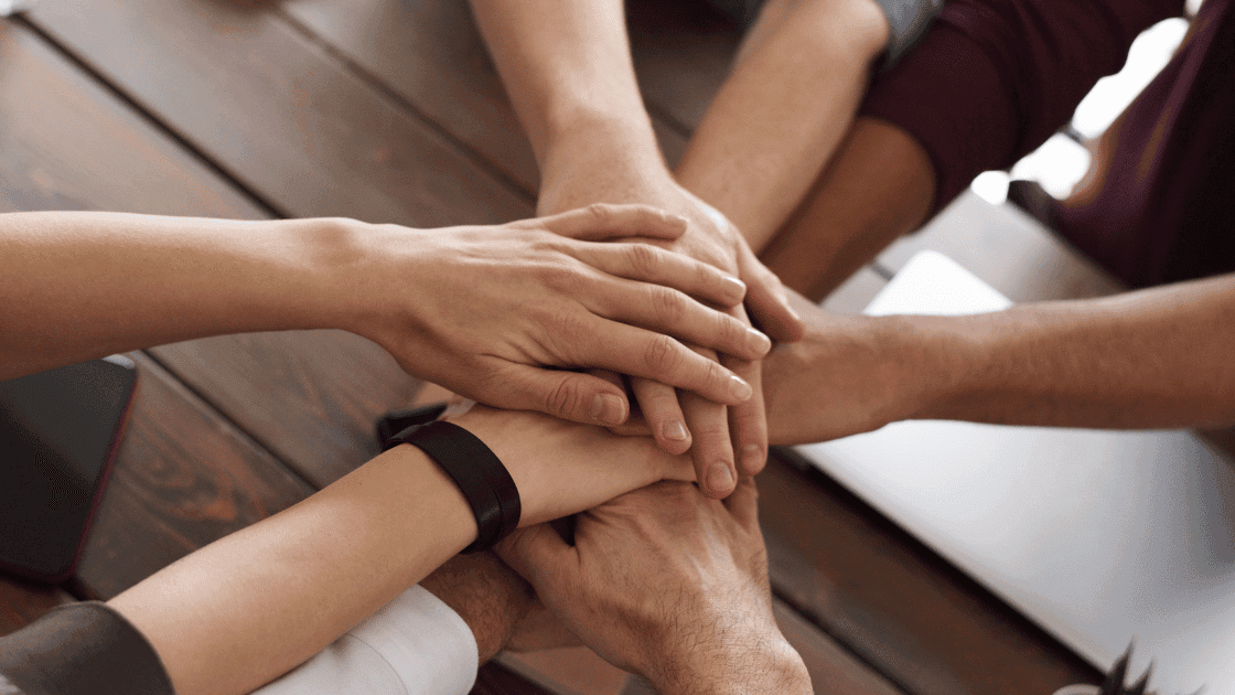 Group of hands stacked together, representing teamwork and collaboration in healthcare.