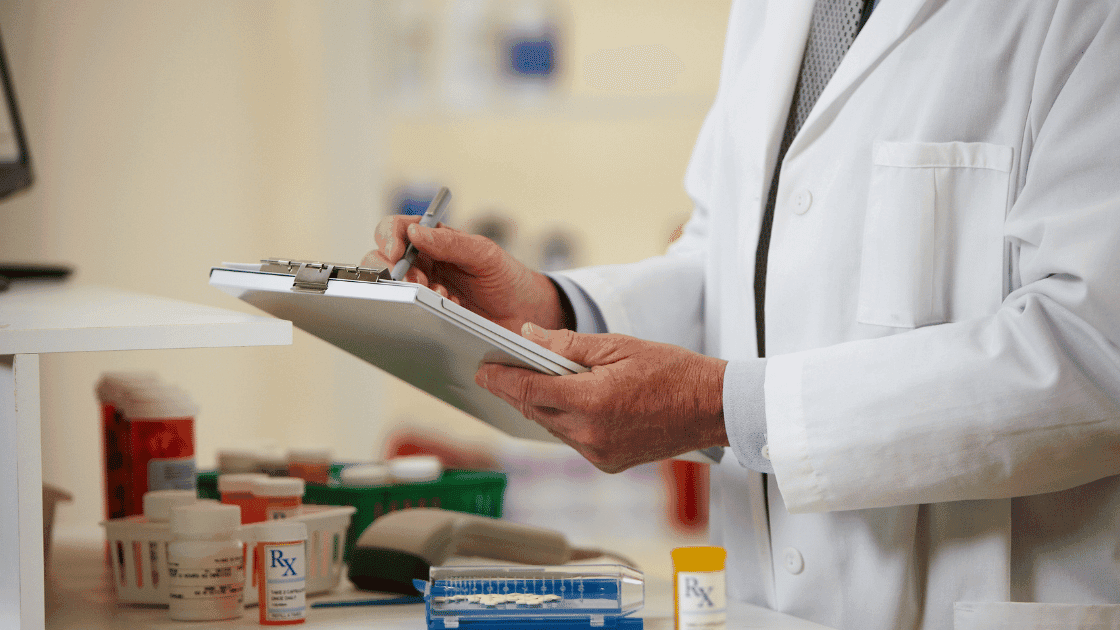 Farmacéutico clínico revisando medicamentos con un portapapeles, enfatizando la gestión de medicamentos para el cuidado de enfermedades crónicas.
